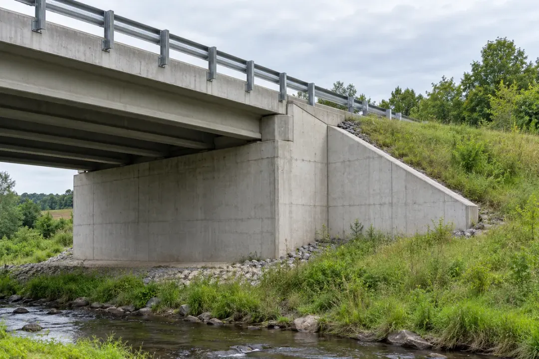 Concrete bridge abutment and wing wall beside an approach embankment.