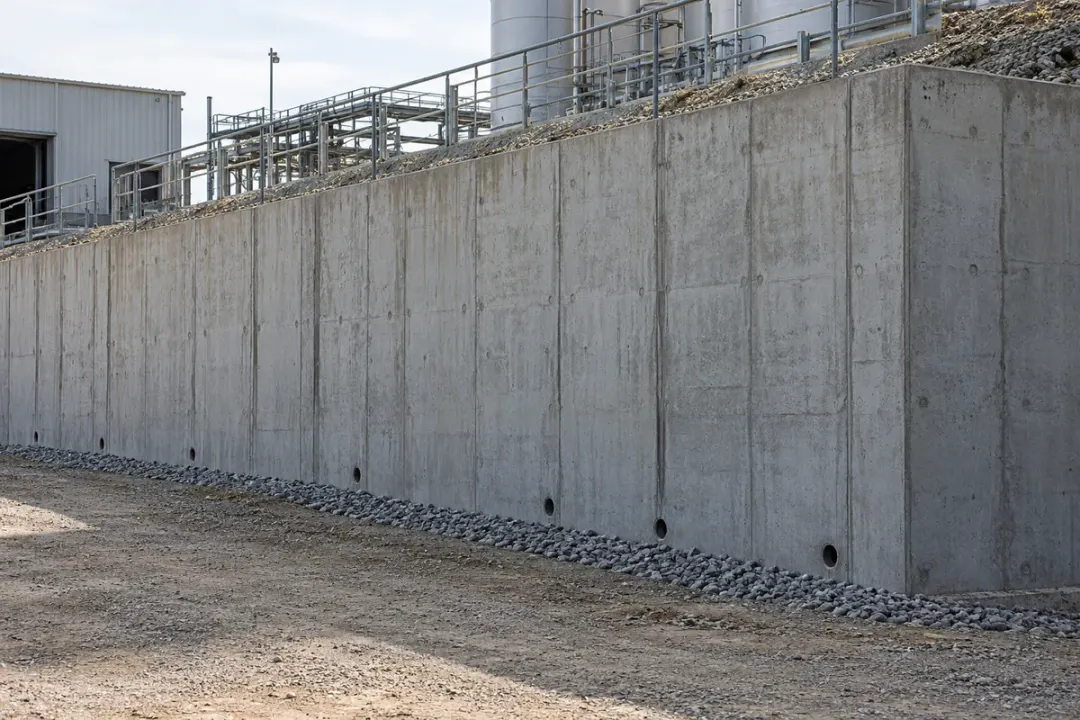 Concrete retaining wall supporting an embankment or industrial platform.