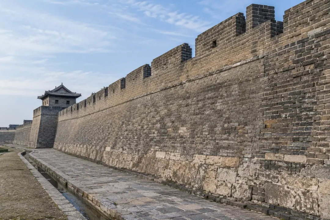 Historic masonry wall with visible brickwork and a continuous wall profile.