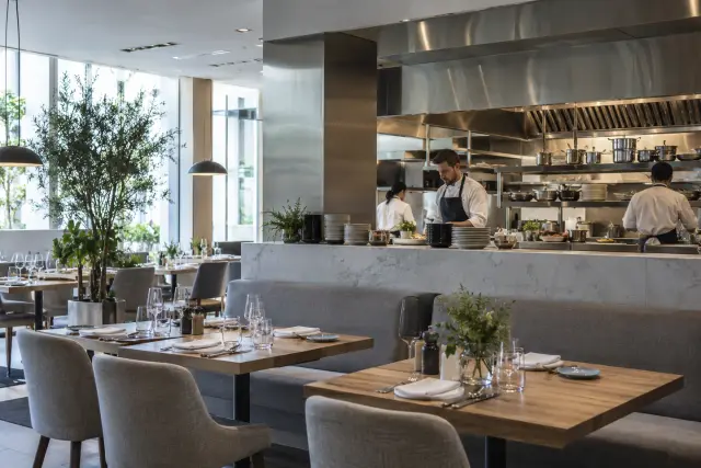 Restaurant dining room beside an open kitchen and extraction hood