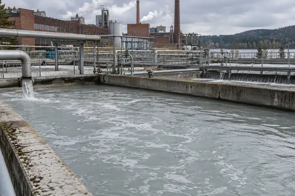 Paper-mill utility yard with water-recovery tanks, transfer pipework and a service walkway