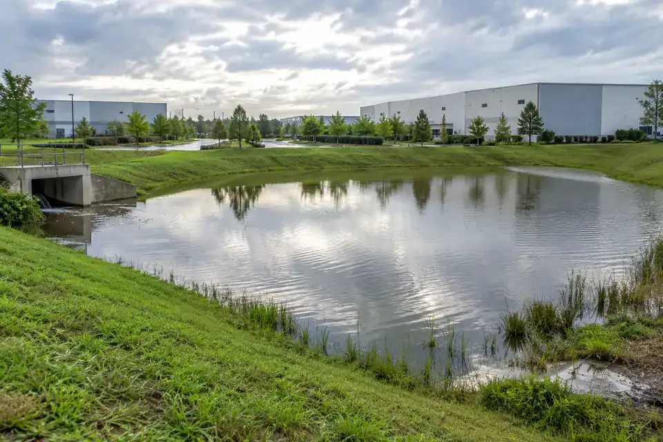 Industrial stormwater-retention basin with a defined outlet structure, vegetated bank and accessible service path