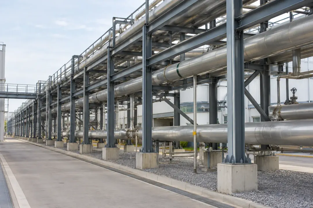 Industrial utility pipe rack with multiple service lines and visible structural columns.