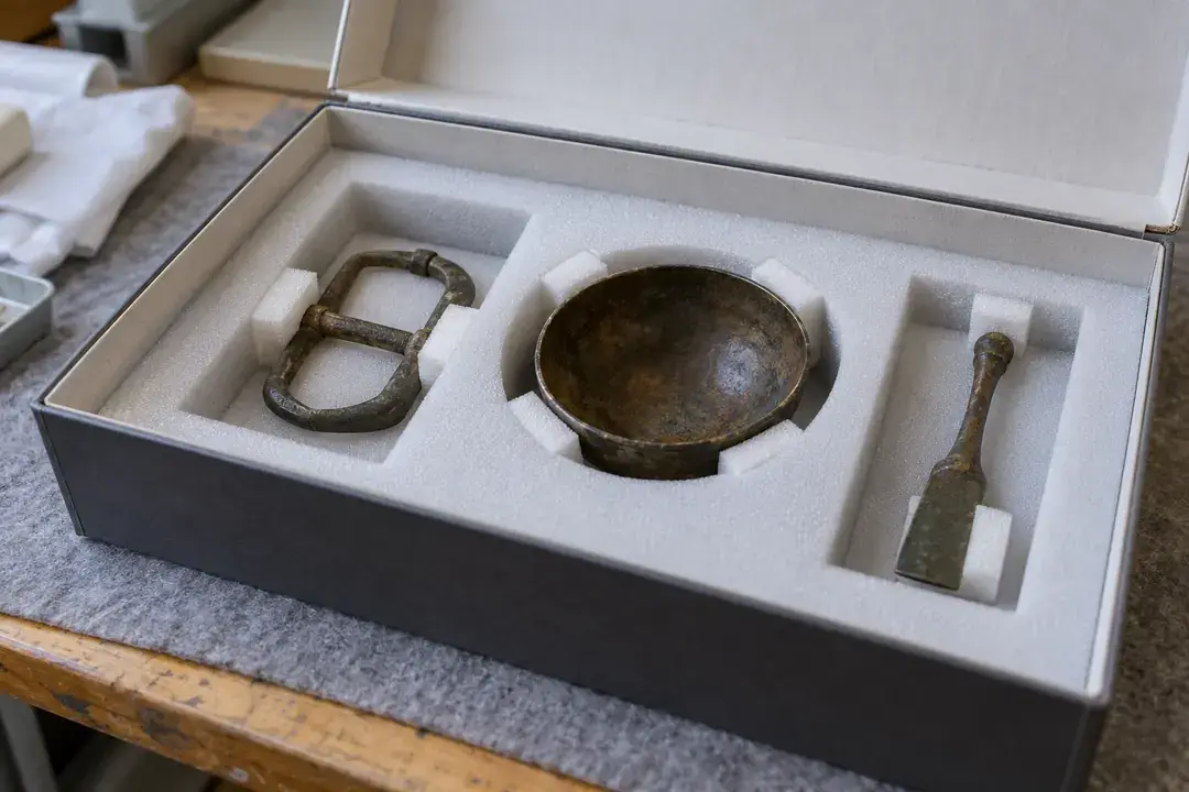 Archaeological bronze objects separated in fitted foam transport supports.